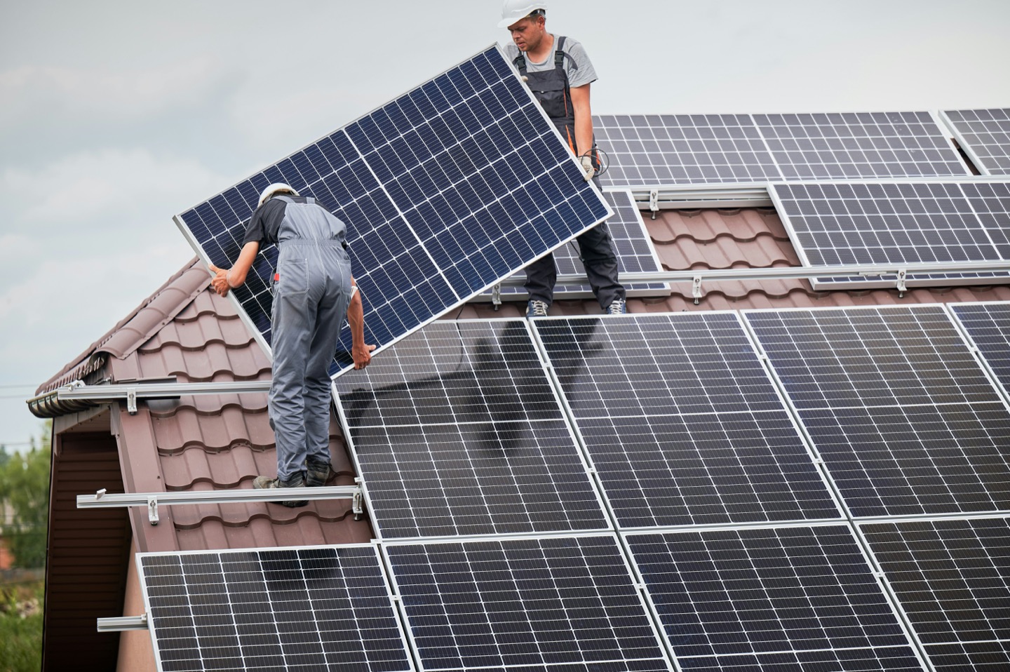 Two solar installers mounting panels on a home roof near Dubuque, Iowa